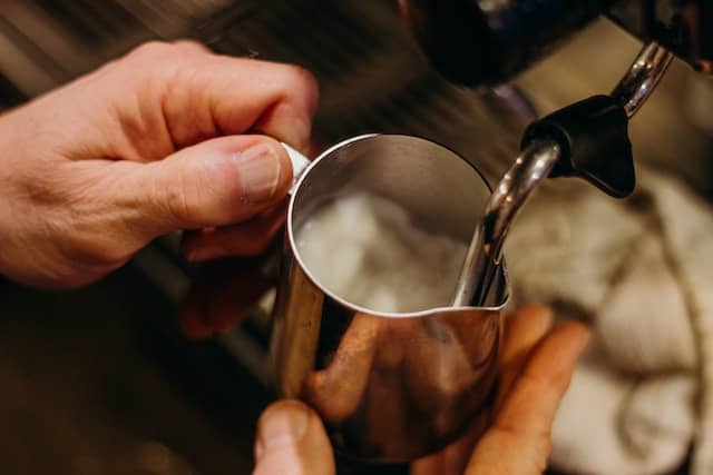 milk being steamed in a metal mug