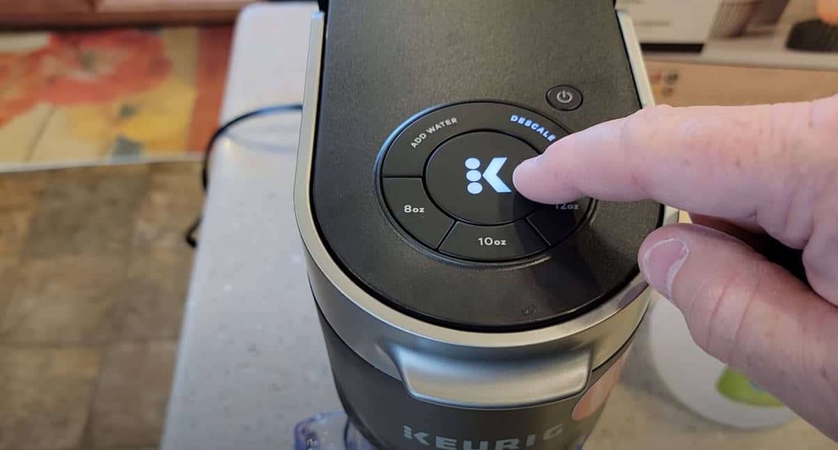 hand on k button of keurig