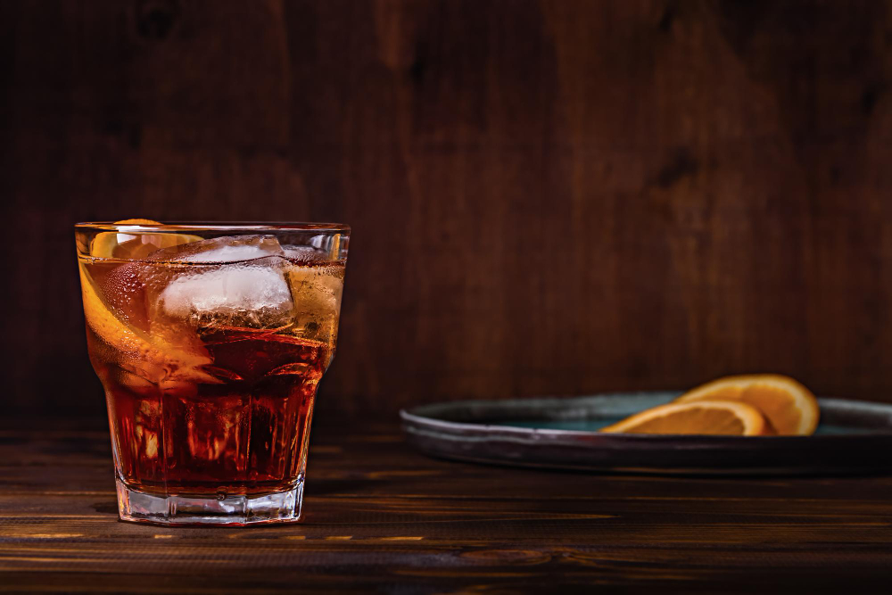 A glass o cold brew Negroni with oranges slices on the side